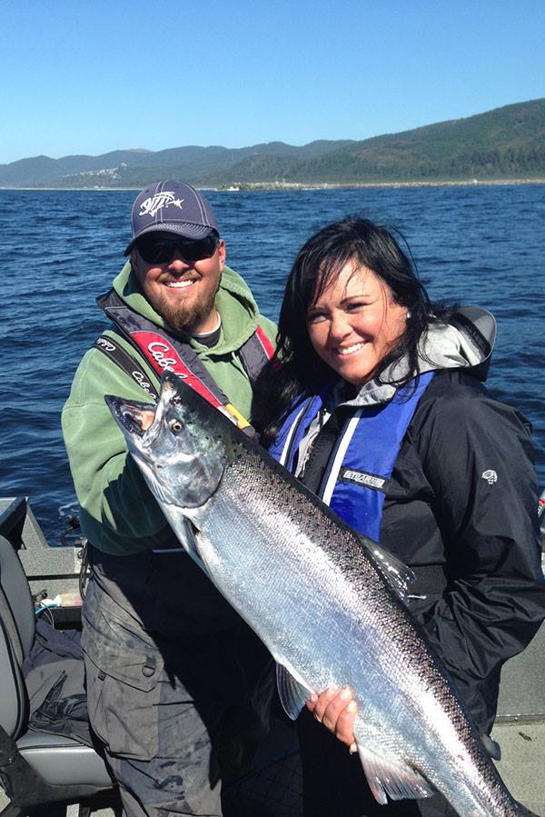 Man and woman show off big fish in a boat