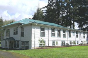Long white building next to pine trees
