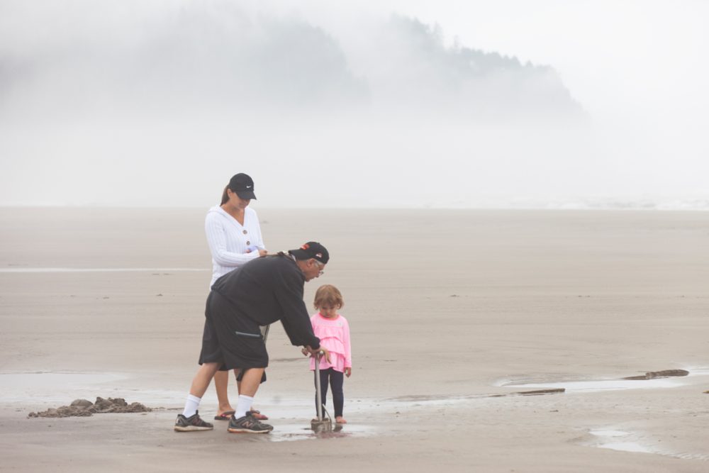 Man, woman and child stand on beach in fog